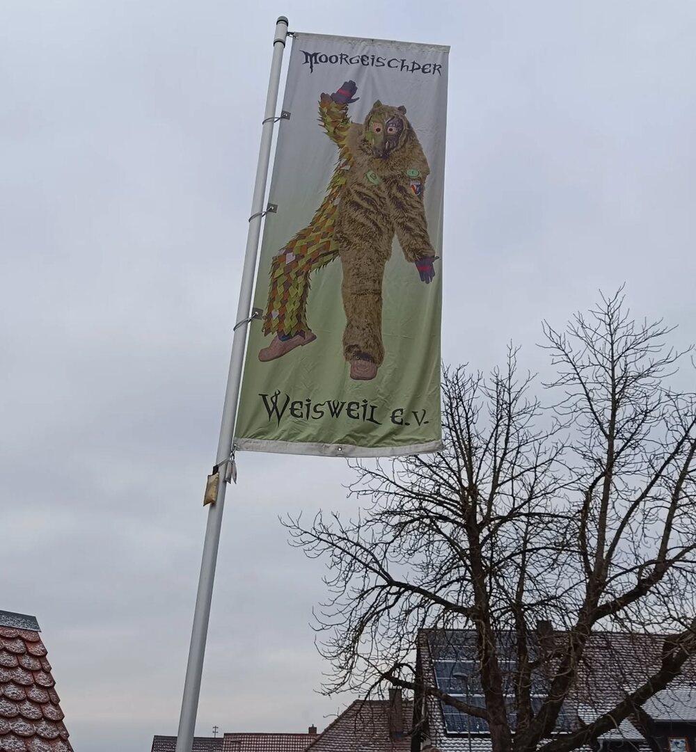 Gehisste Narrenfahne der Moorgeischder Weisweil mit Moorgeischd-Motiv